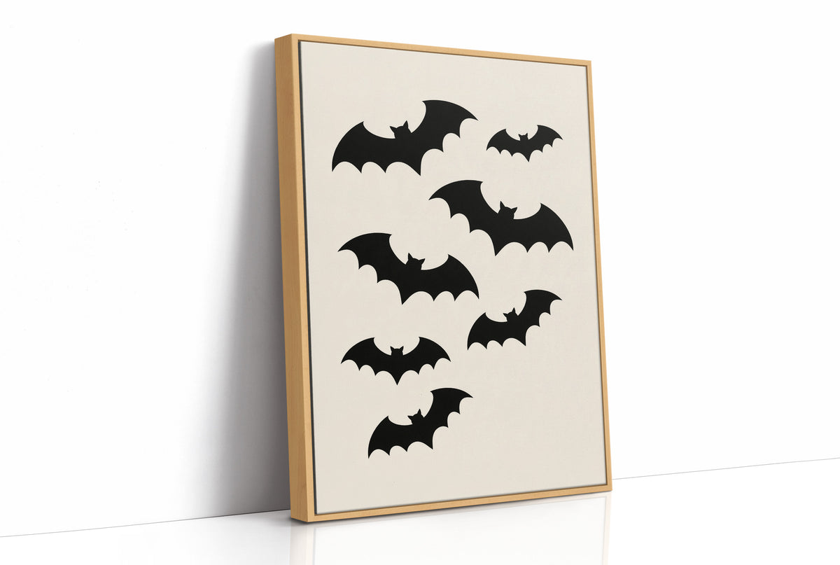 Evening Flight in Silhouette, a loose flock of black bat silhouettes spread across a cream ground in a simple, flat graphic arrangement, as a framed canvas in a natural wood frame