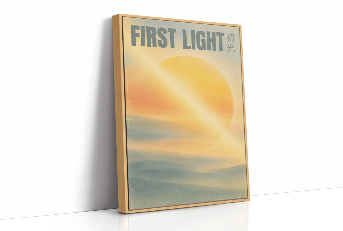 First Light Over a Quiet Sea, a pale sunrise over a soft sea, a warm yellow sun glowing above a band of blue water and peach clouds, with the words FIRST LIGHT in gray capitals across the top and a small Japanese word beside them, as a framed canvas in a natural wood frame
