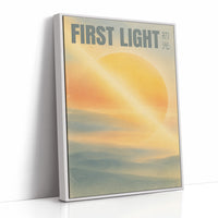 First Light Over a Quiet Sea, a pale sunrise over a soft sea, a warm yellow sun glowing above a band of blue water and peach clouds, with the words FIRST LIGHT in gray capitals across the top and a small Japanese word beside them, as a framed canvas in a white frame