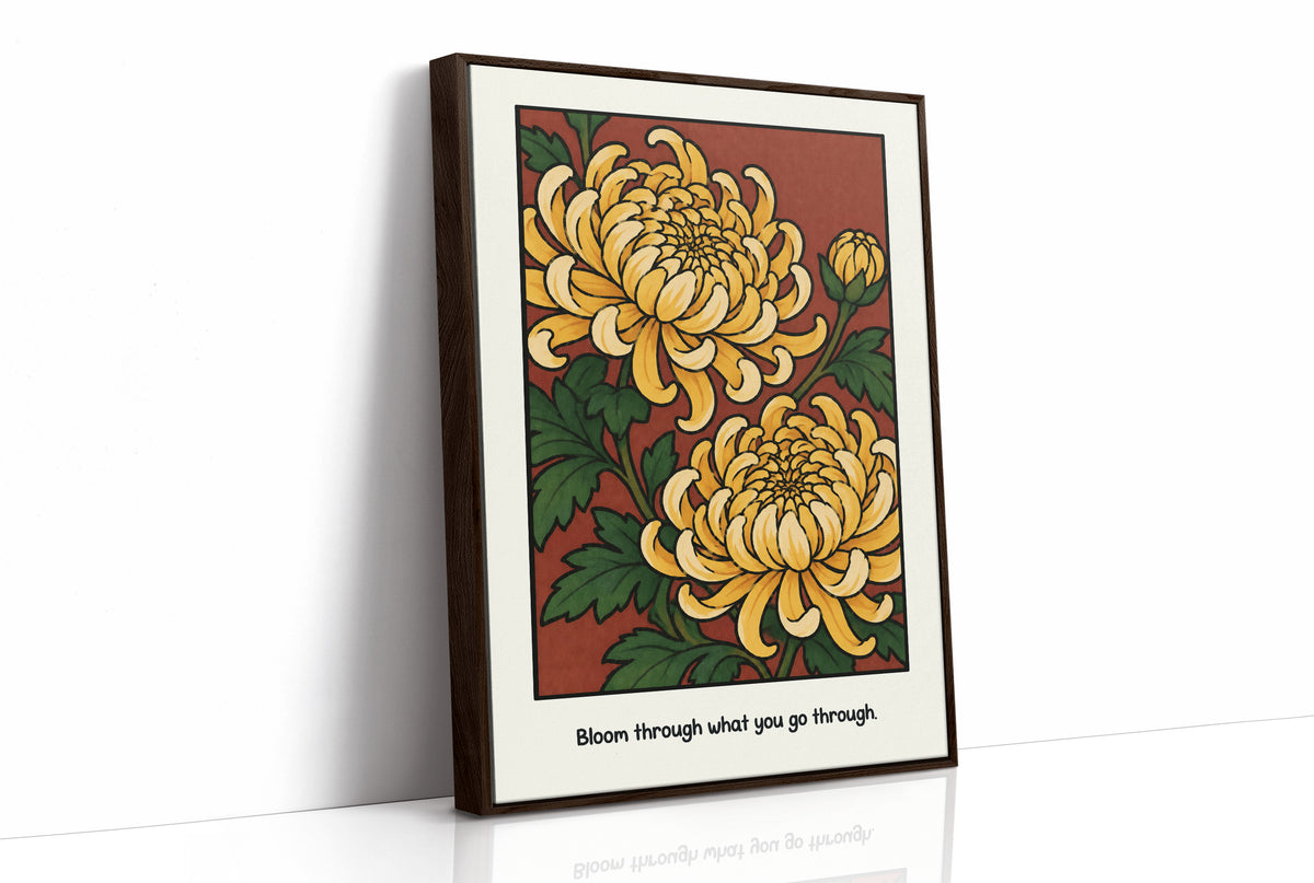 Gold Chrysanthemums Holding Their Ground, a cluster of yellow chrysanthemum blooms with green leaves and a bud on a rust red ground, with the words Bloom through what you go through in small black lettering along the bottom, as a framed canvas in a brown frame