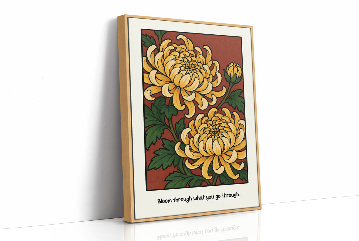 Gold Chrysanthemums Holding Their Ground, a cluster of yellow chrysanthemum blooms with green leaves and a bud on a rust red ground, with the words Bloom through what you go through in small black lettering along the bottom, as a framed canvas in a natural wood frame
