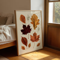Gold Keeps Its Shape, a cluster of pressed autumn leaves in rust, maroon and gold on a cream ground, drawn in a botanical journal style, leaning on a wood floor in a bedroom beside white linen bedding