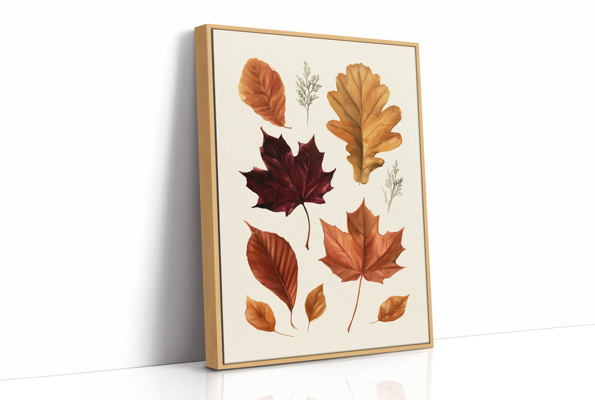 Gold Keeps Its Shape, a cluster of pressed autumn leaves in rust, maroon and gold on a cream ground, drawn in a botanical journal style, as a framed canvas in a natural wood frame