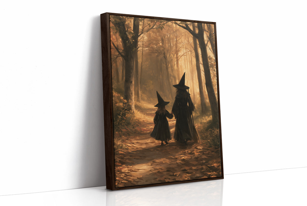 Hand in Hand Through the Woods, two witches in pointed hats walking hand in hand down a path through an autumn forest, one tall and one small, painted in gold, rust and deep shadow, as a framed canvas in a brown frame