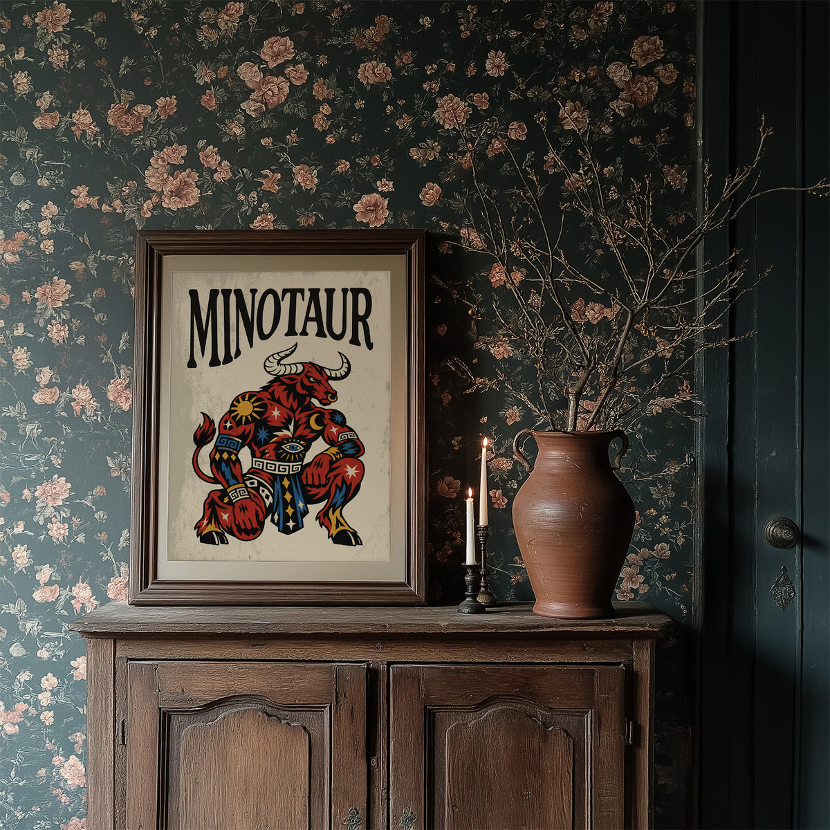 Horns in the Labyrinth, a red and patterned minotaur seated with a braced stance and a horned head, painted in bold black outlines on a cream paper ground beneath bold black lettering, in a traditional tattoo flash style, in a dark wood frame on a floral wallpaper wall above a rustic cabinet and a vase