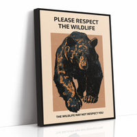 Keep a Respectful Distance, a large black bear with amber and brown fur, head low and shoulders bunched, set on a tan ground under bold black lettering that reads PLEASE RESPECT THE WILDLIFE in a vintage warning sign style, as a framed canvas in a black frame