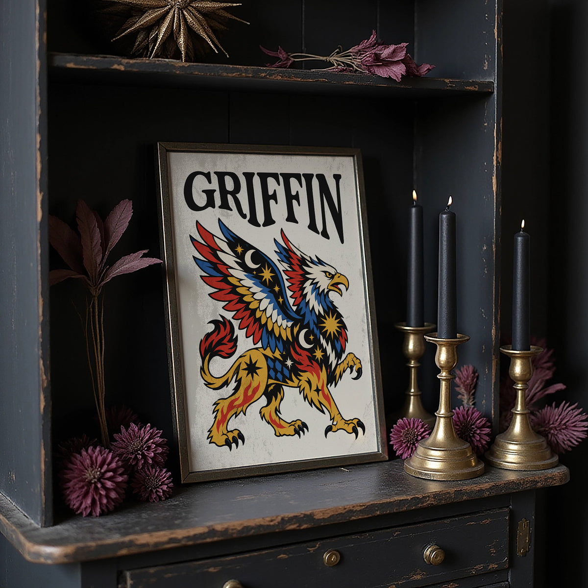 Keeper of the Gilded Gate, a winged lion guardian with a golden body, red and blue feathers and a black lettered name across the top, in a bold flash sheet style on cream parchment, in a dark frame on a black shelf beside brass candles and dried leaves