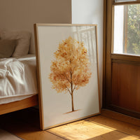 Keeping Its Warmth a Little Longer, a single watercolor tree in amber and rust with a soft brown trunk on a cream ground, the leaves painted in loose soft strokes, leaning on a wood floor in a bedroom beside white linen bedding