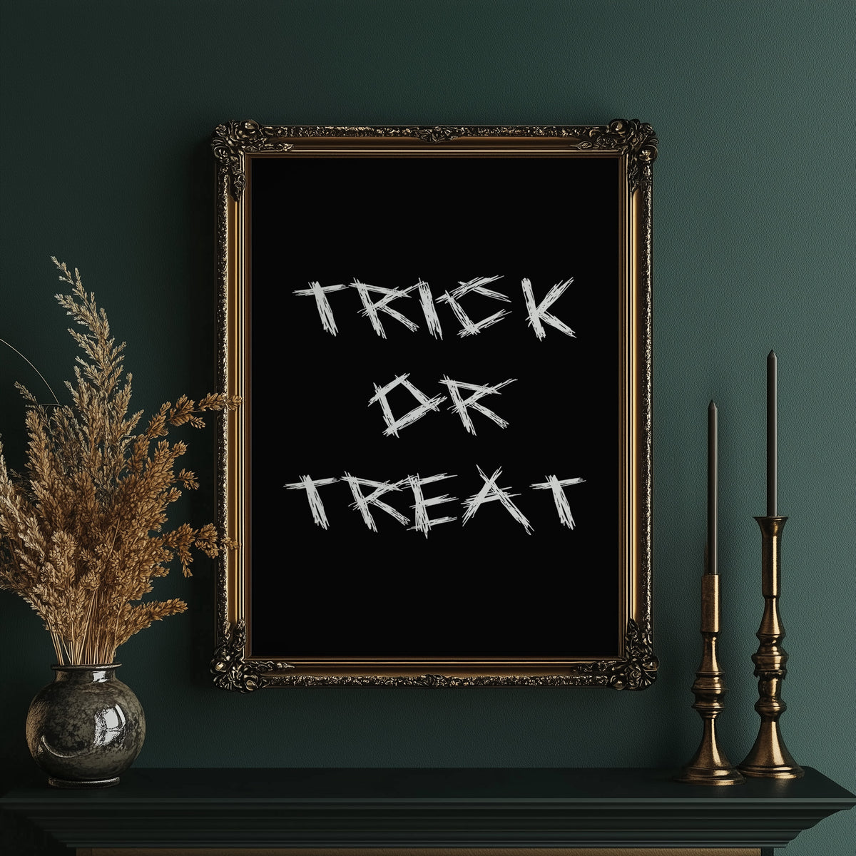 Knock Once for the Sweets, bold chalky white lettering reading TRICK OR TREAT on a solid black ground, hand lettered with a worn brush texture, in an ornate gold frame on a deep green wall beside tall brass candlesticks
