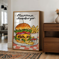Mmmm Cheeseburger Makes Everything Better, a stacked cheeseburger with lettuce, tomato, cheese and a sesame bun beside fries and ketchup cups on a red and white checkered plate, with the lettering Mmmmm cheeseburger in black script across the top, in a wood frame on a wall beside a walnut cabinet and an open doorway