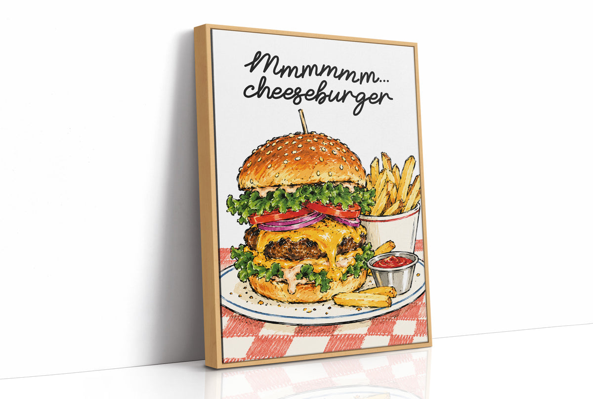 Mmmm Cheeseburger Makes Everything Better, a stacked cheeseburger with lettuce, tomato, cheese and a sesame bun beside fries and ketchup cups on a red and white checkered plate, with the lettering Mmmmm cheeseburger in black script across the top, as a framed canvas in a natural wood frame