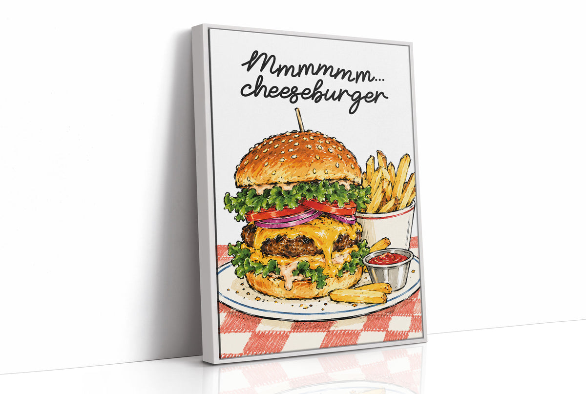 Mmmm Cheeseburger Makes Everything Better, a stacked cheeseburger with lettuce, tomato, cheese and a sesame bun beside fries and ketchup cups on a red and white checkered plate, with the lettering Mmmmm cheeseburger in black script across the top, as a framed canvas in a white frame