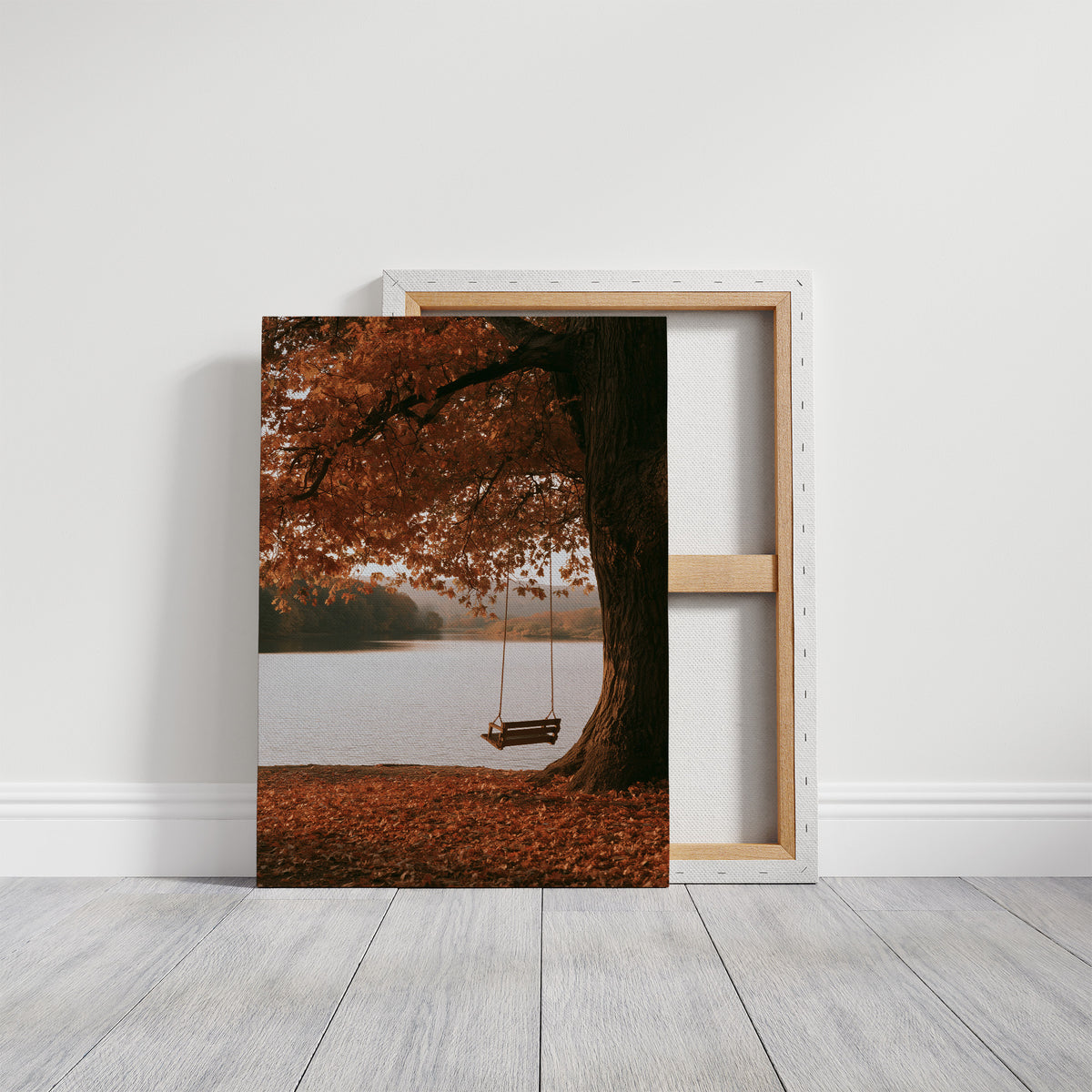 Nobody Has Swung Since Morning, a lone wooden swing hanging from a great tree with orange leaves above a still lake, painted in burnt orange, rust and misty gray, on a gallery canvas with wrapped edges leaning against a white wall