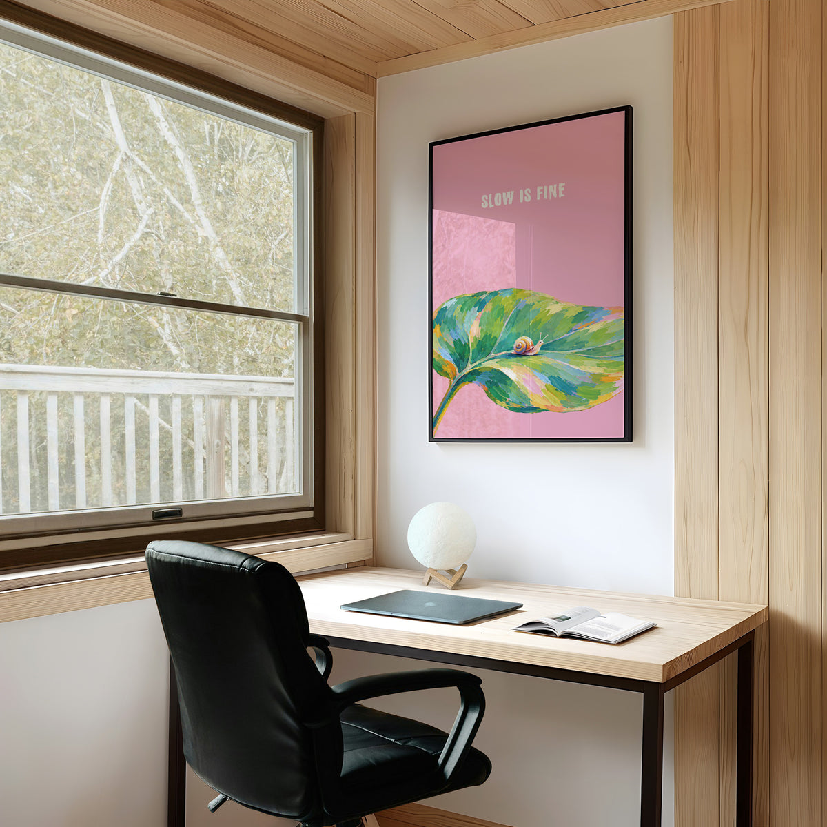 Nothing Here Is Rushed, a green leaf curling across the lower half of a blush pink ground with a small snail resting on its curve, with a pale line of lettering above, in a loose watercolor style painted in blush pink, green and soft gold, on a study wall above a writing desk and a black desk chair