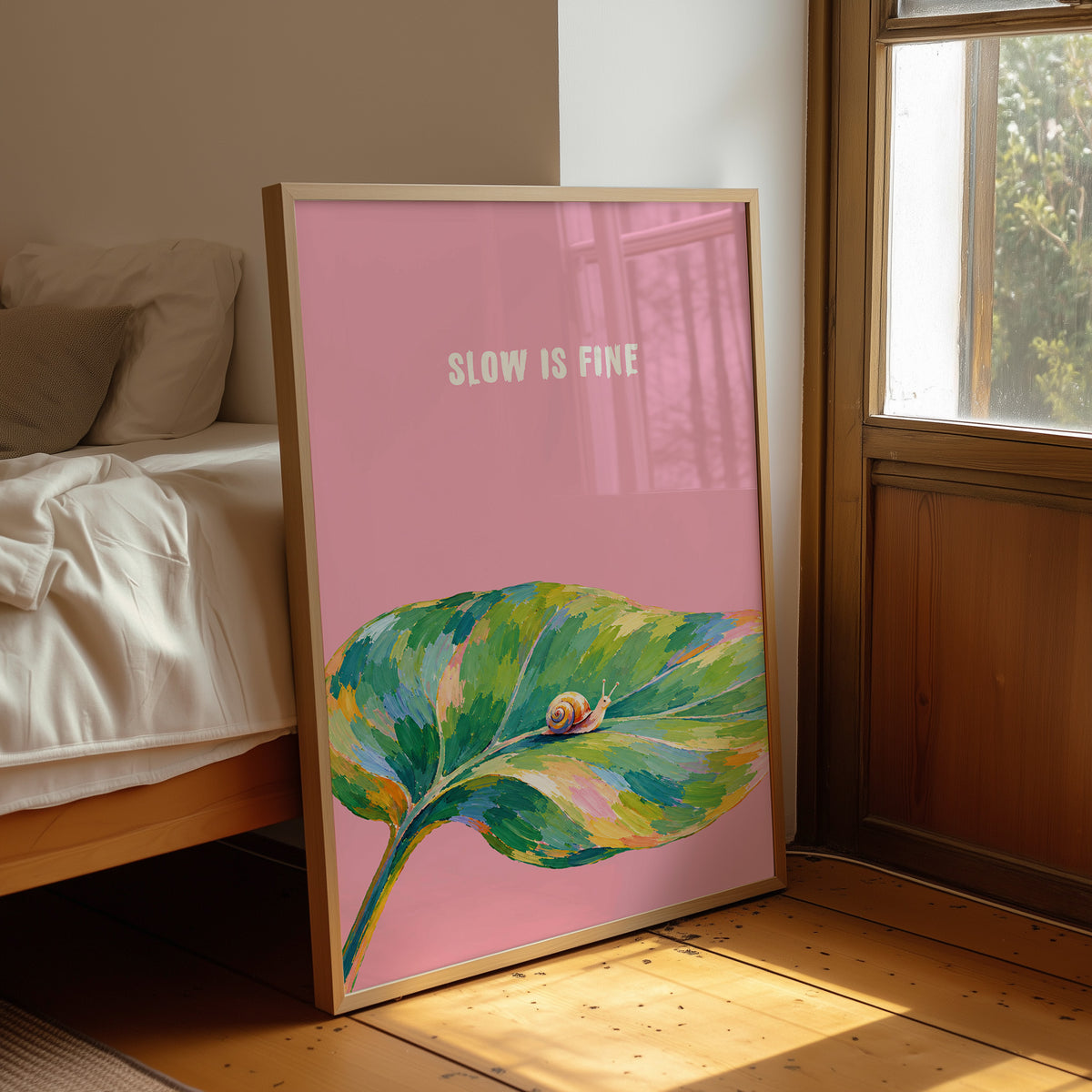 Nothing Here Is Rushed, a green leaf curling across the lower half of a blush pink ground with a small snail resting on its curve, with a pale line of lettering above, in a loose watercolor style painted in blush pink, green and soft gold, leaning on a wood floor in a bedroom beside white linen bedding