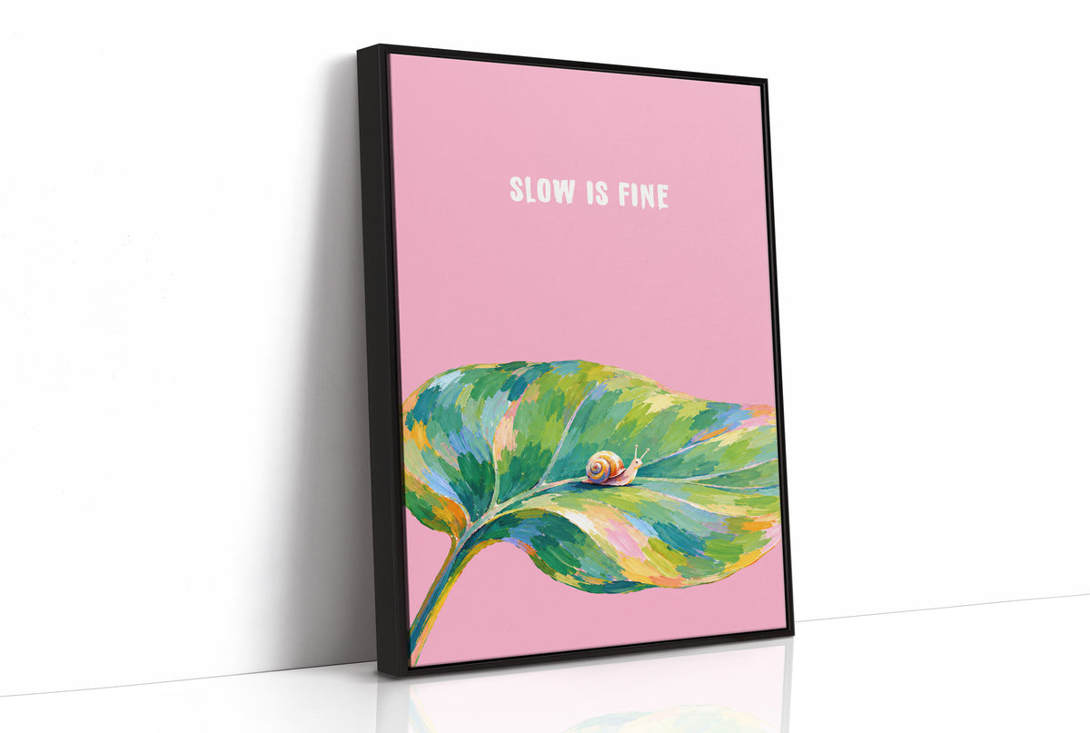 Nothing Here Is Rushed, a green leaf curling across the lower half of a blush pink ground with a small snail resting on its curve, with a pale line of lettering above, in a loose watercolor style painted in blush pink, green and soft gold, as a framed canvas in a black frame