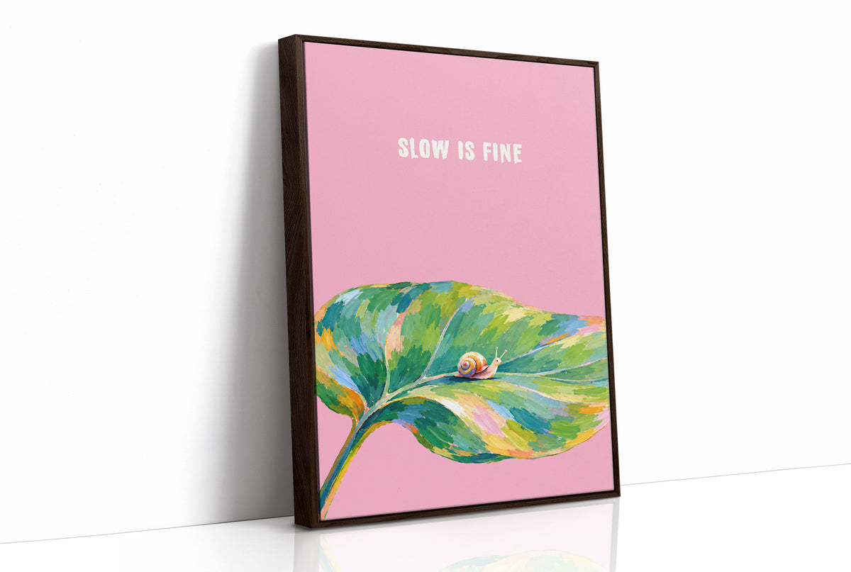 Nothing Here Is Rushed, a green leaf curling across the lower half of a blush pink ground with a small snail resting on its curve, with a pale line of lettering above, in a loose watercolor style painted in blush pink, green and soft gold, as a framed canvas in a brown frame