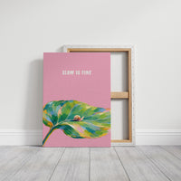Nothing Here Is Rushed, a green leaf curling across the lower half of a blush pink ground with a small snail resting on its curve, with a pale line of lettering above, in a loose watercolor style painted in blush pink, green and soft gold, on a gallery canvas with wrapped edges leaning against a white wall