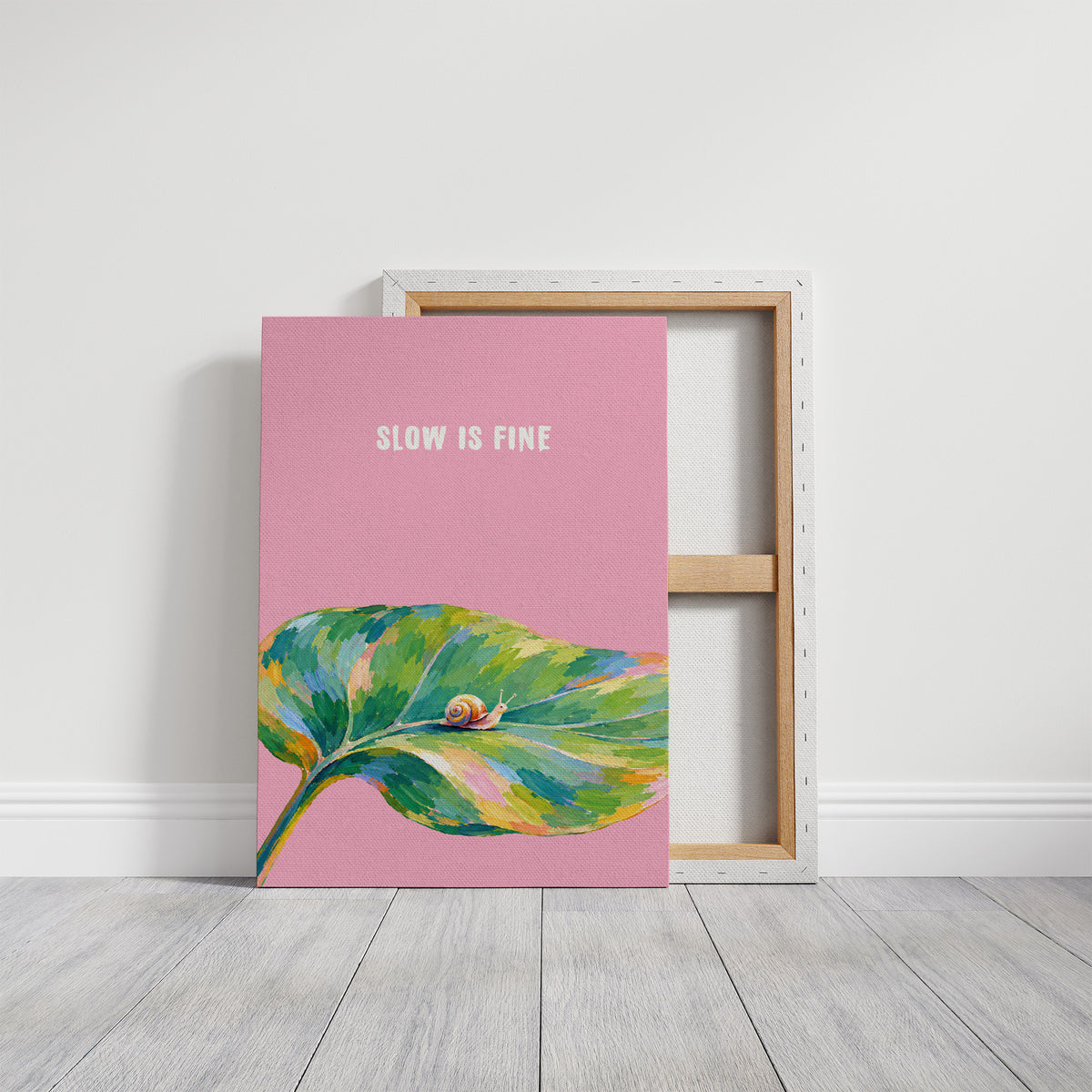 Nothing Here Is Rushed, a green leaf curling across the lower half of a blush pink ground with a small snail resting on its curve, with a pale line of lettering above, in a loose watercolor style painted in blush pink, green and soft gold, on a gallery canvas with wrapped edges leaning against a white wall