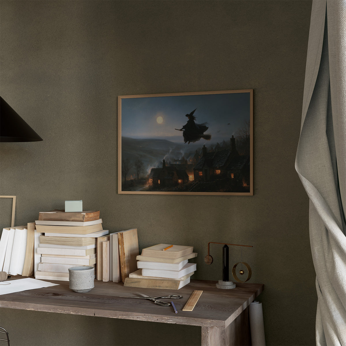 Over the Lantern Village, a witch flying across a full moon above a lantern lit village on a misty hillside, painted in midnight blue, pale moon gold and soft smoke gray, in a thin wood frame on a moss green wall above a desk stacked with books