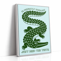 Perfectly Harmless, Mind the Teeth, a deep green crocodile curling down a pale mint ground, with a bold hand lettered line above reading I'M PERFECTLY HARMLESS and one below reading JUST MIND THE TEETH, as a framed canvas in a white frame