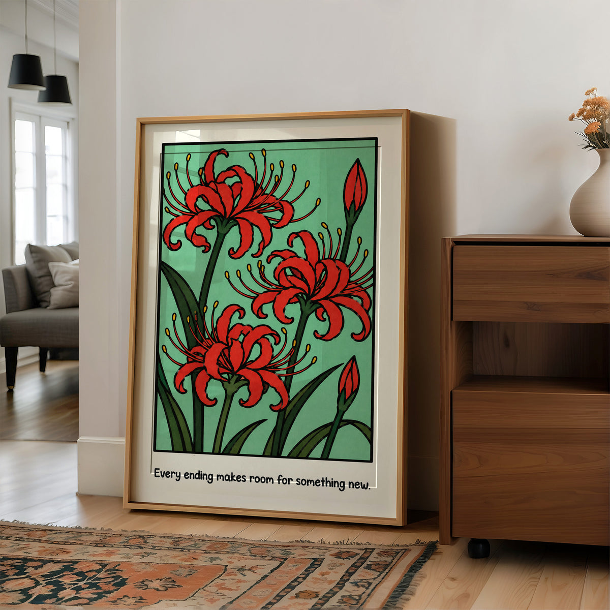 Red Lilies Make Room for Something New, red spider lily blooms with buds and dark green stems on a soft green ground, with the words Every ending makes room for something new in small black lettering along the bottom, in a wood frame on a wall beside a walnut cabinet and an open doorway