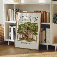 Roots That Remember the Ground, a banyan tree with a wide green canopy and many aerial roots hanging to the ground, drawn in a framed Japanese travel poster style with katakana above and BANYAN TREE below, in a wood frame on a white bookshelf beside stacked books and a small basket