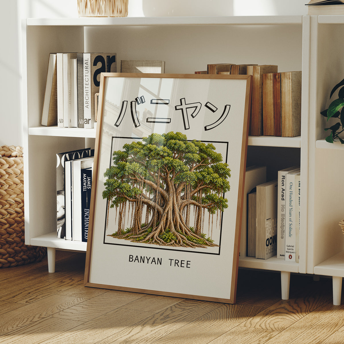 Roots That Remember the Ground, a banyan tree with a wide green canopy and many aerial roots hanging to the ground, drawn in a framed Japanese travel poster style with katakana above and BANYAN TREE below, in a wood frame on a white bookshelf beside stacked books and a small basket
