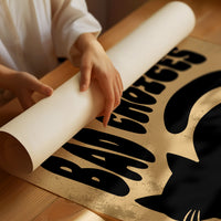 Sleek Silhouette, Questionable Taste, a solid black cat silhouette with a long tail curled up the side, standing on tan paper with the words GOOD KITTY BAD CHOICES in bold black lettering, as a matte poster, unframed