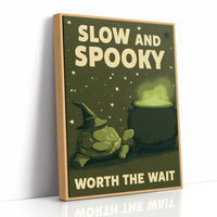 Slow and Spooky, Worth the Wait, a green cartoon creature in a witch hat beside a bubbling cauldron, bold cream lettering reading SLOW AND SPOOKY WORTH THE WAIT, as a framed canvas in a natural wood frame