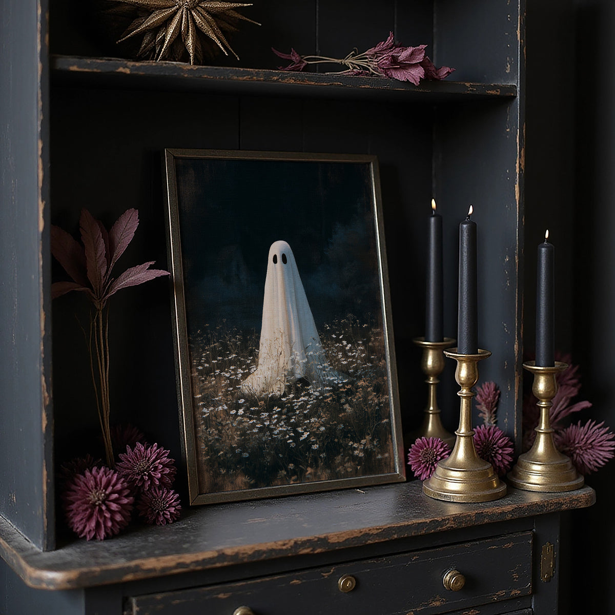 Someone Stayed Behind in the Meadow, a small white ghost standing in a dark field of pale wildflowers beneath a black woodland, painted in deep green, charcoal and bone, in a dark frame on a black shelf beside brass candles and dried leaves