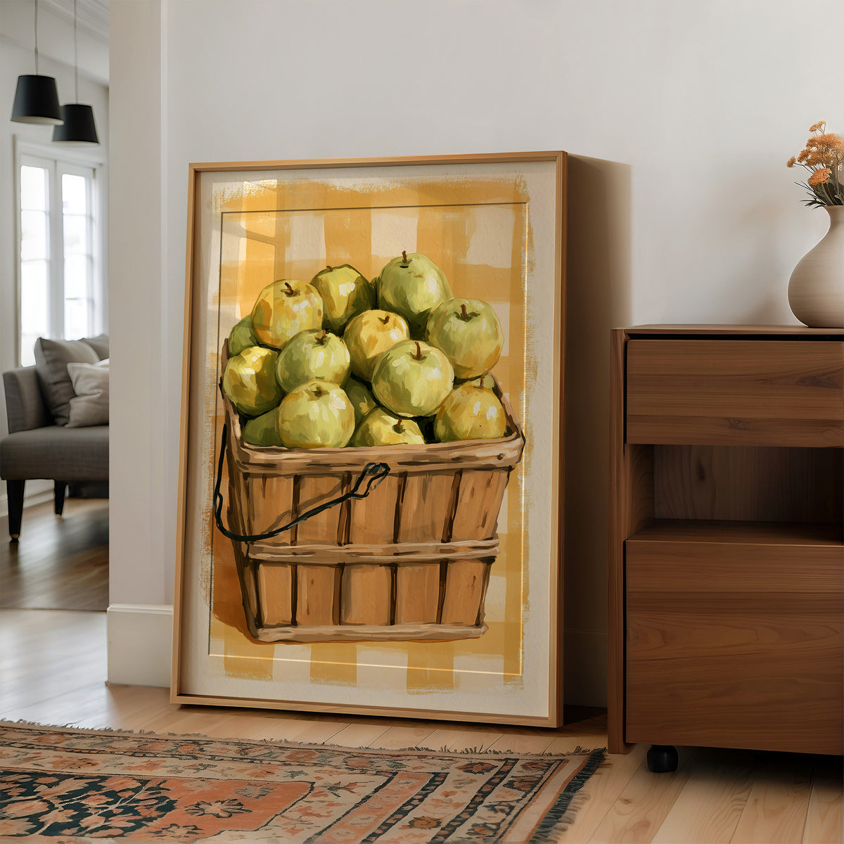 Something Sweet Waits in the Basket, a basket heaped with pale green pears on a soft yellow gingham ground, painted in lemon, sage and warm tan, in a wood frame on a wall beside a walnut cabinet and an open doorway