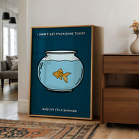 Still Enough for Today, a round glass fishbowl with one goldfish on a deep navy ground, a line of cream lettering above and below in a cartoon style, painted in navy, pale blue and orange, in a wood frame on a wall beside a walnut cabinet and an open doorway