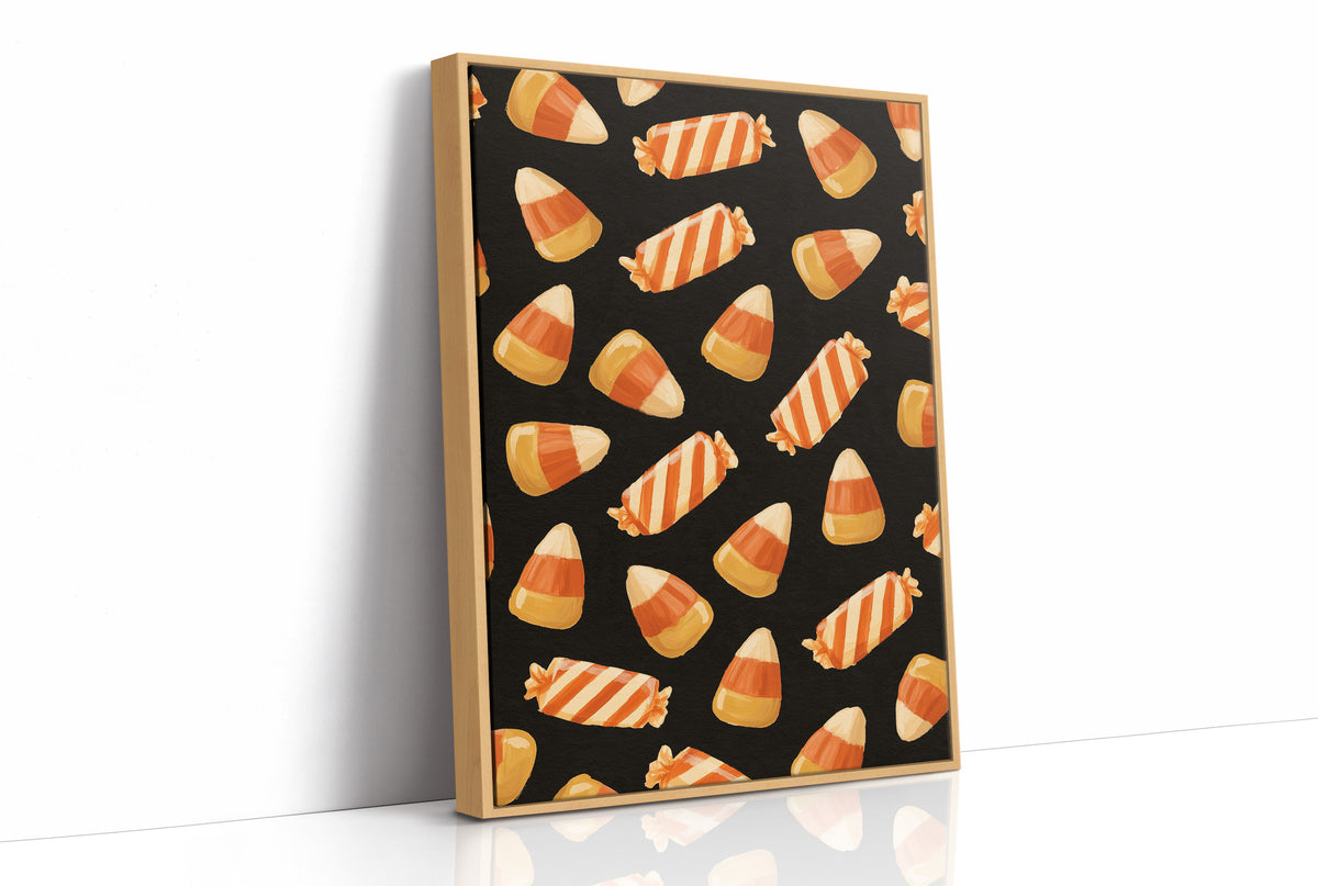 Stripes Kept for Later, a repeating pattern of candy corn kernels in cream, orange and butter yellow on a deep black ground, as a framed canvas in a natural wood frame