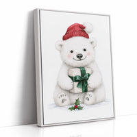 The Bear Cub Keeps a Secret, a small polar bear cub in a red knit hat hugging a green wrapped gift with a sprig of holly at its feet, on a soft cream ground, as a framed canvas in a white frame