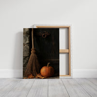 The Broom Waits by the Door, a straw broom leaning in a dim corner beside a single orange pumpkin, painted in charcoal, rust and amber, on a gallery canvas with wrapped edges leaning against a white wall