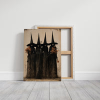 The Coven Keeps Its Silence, five witches in tall pointed hats standing shoulder to shoulder, painted in black, charcoal and dusty cream, on a gallery canvas with wrapped edges leaning against a white wall