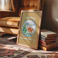 The Goldfish Takes the Afternoon, a goldfish circling a round bowl of pale blue water with green plants, with three lines of cream lettering on a mustard ground, in a flat playful illustrated style painted in mustard, blue and cream, in a wood frame on a rug beside a leather armchair and a stack of books