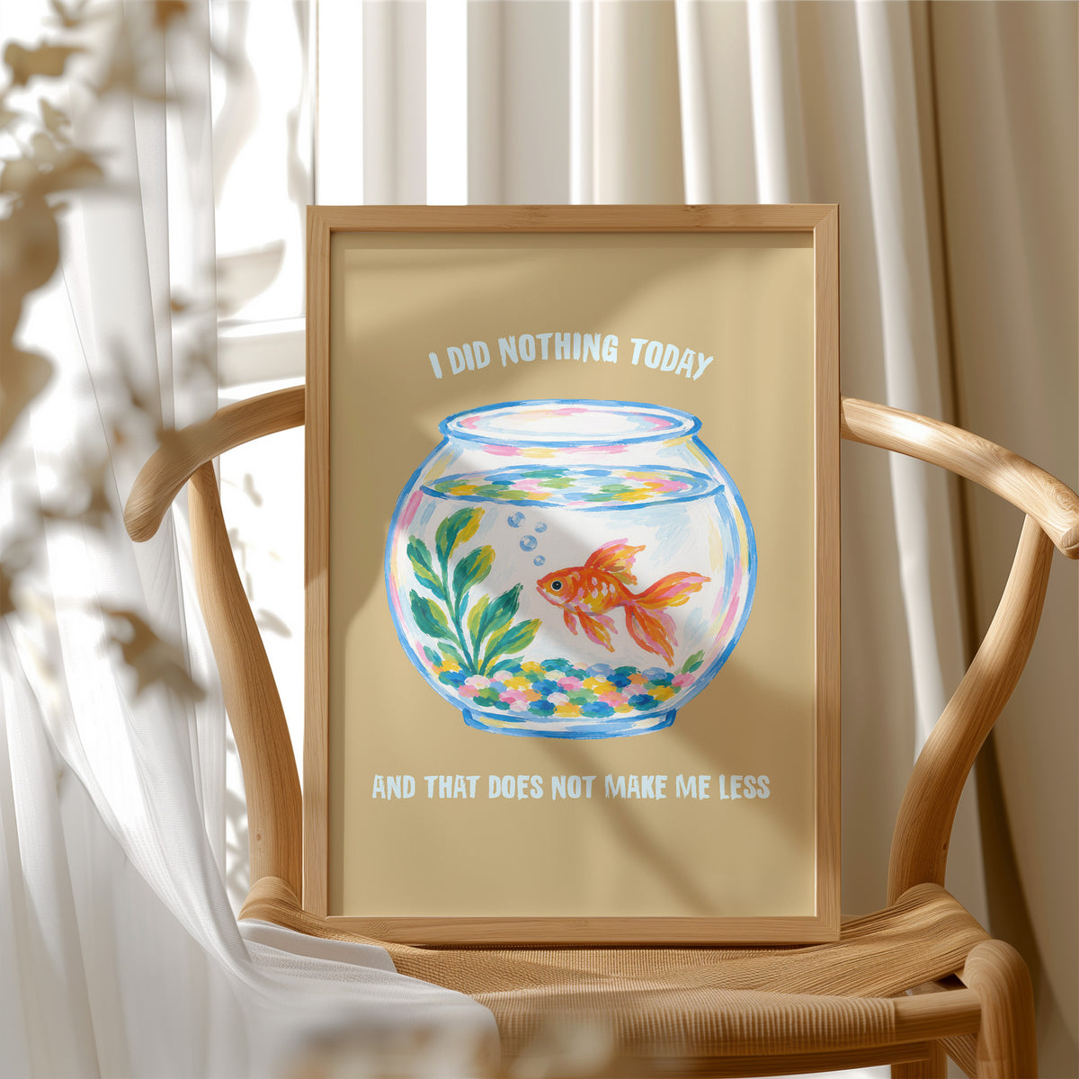 The Goldfish Takes the Afternoon, a goldfish circling a round bowl of pale blue water with green plants, with three lines of cream lettering on a mustard ground, in a flat playful illustrated style painted in mustard, blue and cream, in a wood frame beside a wicker chair by a sunny window