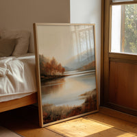 The Lake Remembers Autumn, an autumn lake at dusk with a line of turning trees on the near shore and pale mountains beyond, the water mirroring the sky in soft blue and amber, leaning on a wood floor in a bedroom beside white linen bedding