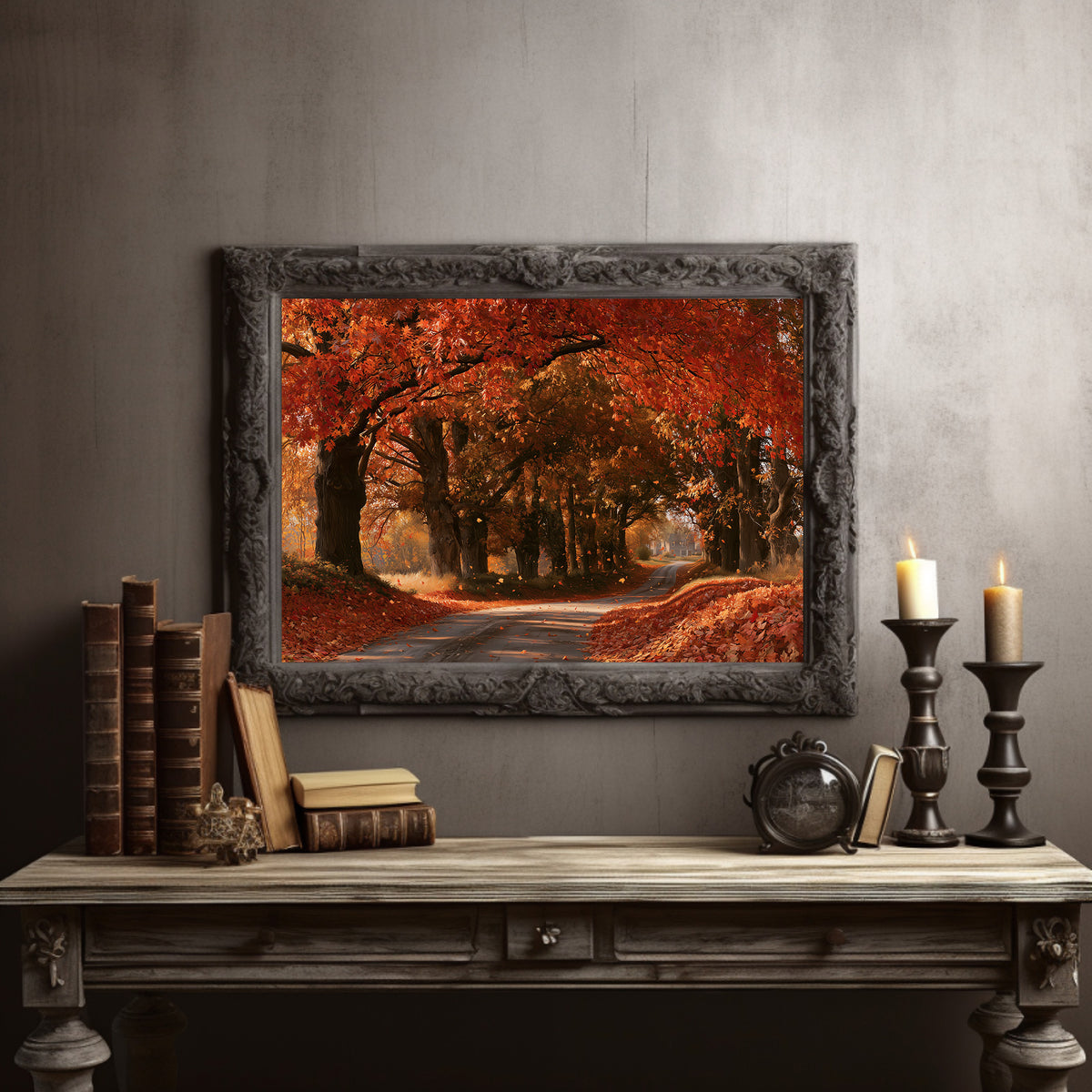 The Lane Forgets It Is Summer, tree lined country road under flame orange autumn maples painting, in a dark carved frame on a gray wall above a console table with candlesticks and old books
