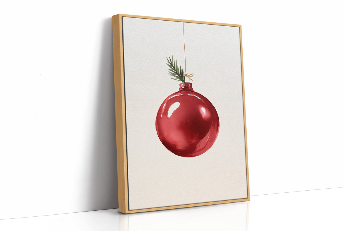 The Last Bauble on the Branch, a single red glass ornament hanging from a thin cord with a sprig of pine tip, on a cream ground, as a framed canvas in a natural wood frame