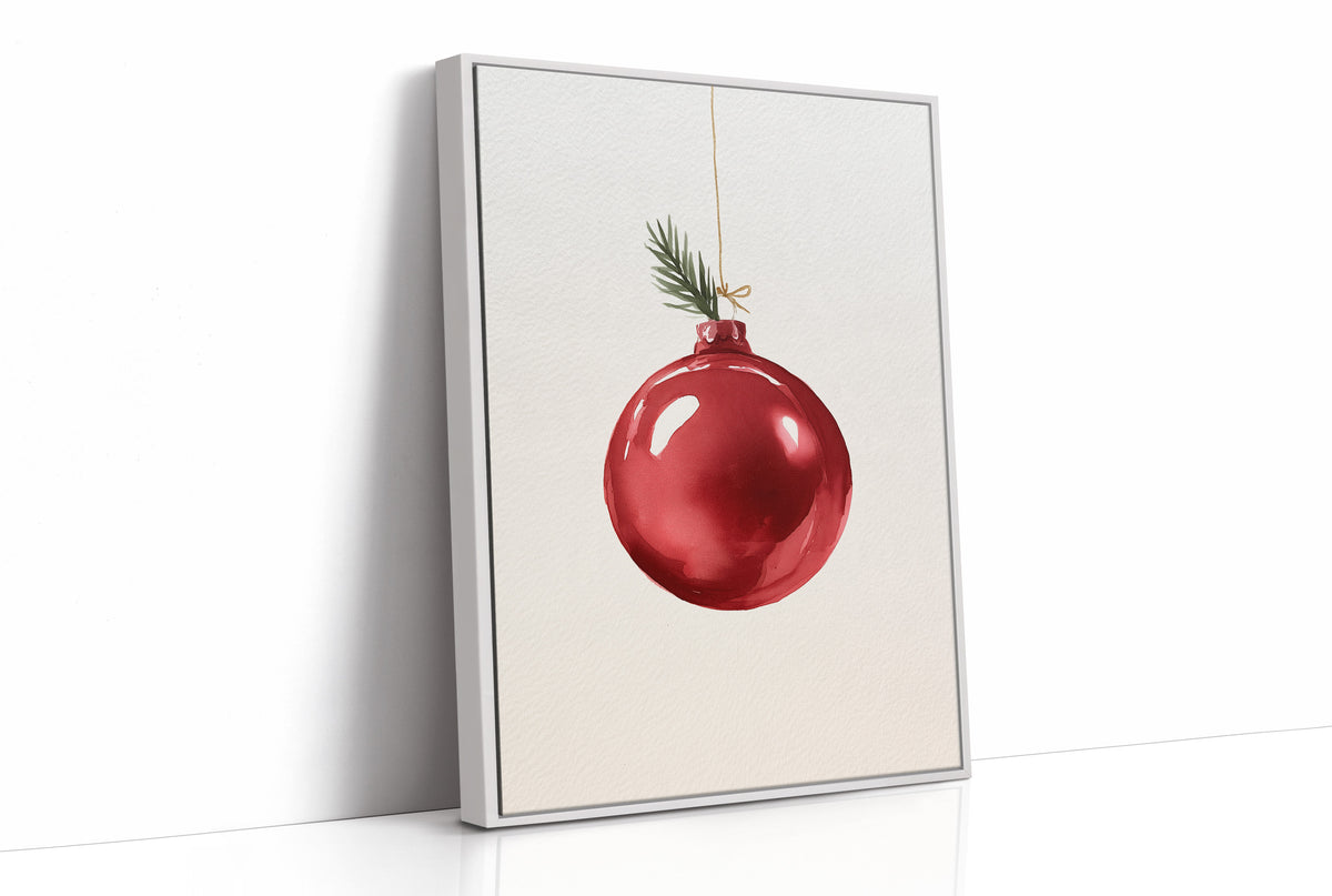The Last Bauble on the Branch, a single red glass ornament hanging from a thin cord with a sprig of pine tip, on a cream ground, as a framed canvas in a white frame