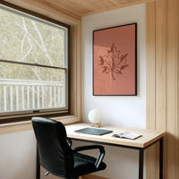 The Maple Keeps Its Last Light, a single maple leaf drawn in fine brown outline on a dusty terracotta ground, a botanical line study with soft shading, on a study wall above a writing desk and a black desk chair