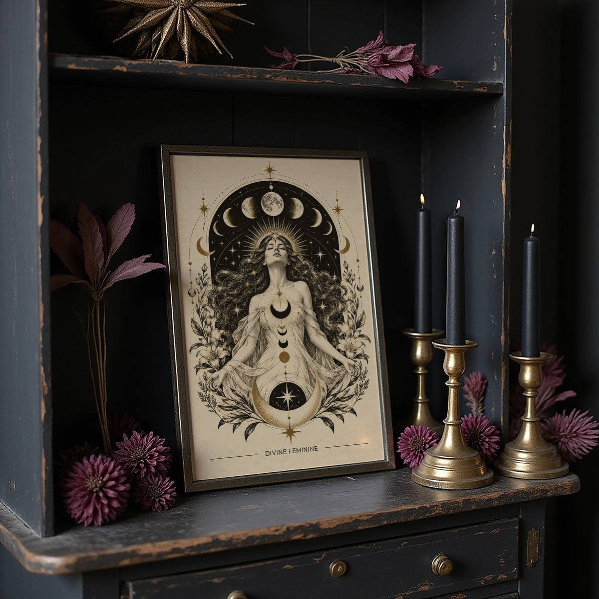The Moon Woven Into Her Hair, a seated woman in quiet meditation crowned with a ring of crescent moons and surrounded by fern fronds, drawn in cream, charcoal and sepia with a deep brown border and small text at the base, in a dark frame on a black shelf beside brass candles and dried leaves