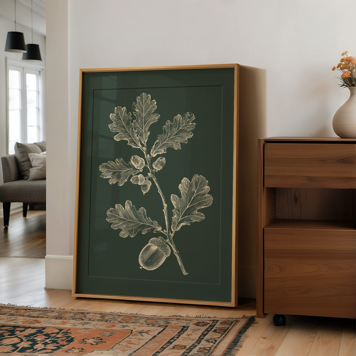 The Oak Keeps Its Harvest Close, a sprig of lobed oak leaves and three acorns drawn in pale cream lines on a deep forest green ground, in a botanical study style, in a wood frame on a wall beside a walnut cabinet and an open doorway