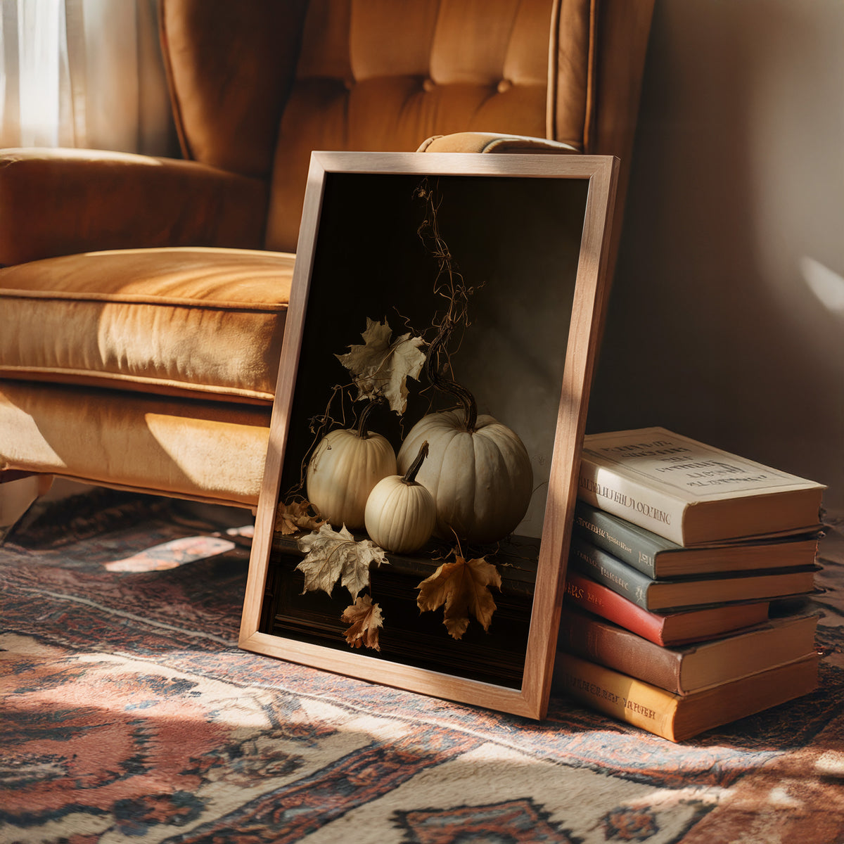 The Pale Ones Keep Their Vigil, three pale pumpkins and a few gold oak leaves in a still life on a deep black ground, with dried vine stems curling above, painted in cream, ochre and charcoal, in a wood frame on a rug beside a leather armchair and a stack of books