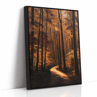 The Path Bends Toward Home, an autumn forest path winding between tall dark trunks, lit by a shaft of golden light across the leaves, painted in rust, amber and deep brown, as a framed canvas in a black frame