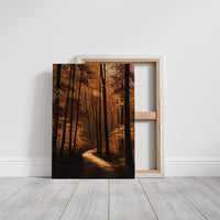 The Path Bends Toward Home, an autumn forest path winding between tall dark trunks, lit by a shaft of golden light across the leaves, painted in rust, amber and deep brown, on a gallery canvas with wrapped edges leaning against a white wall