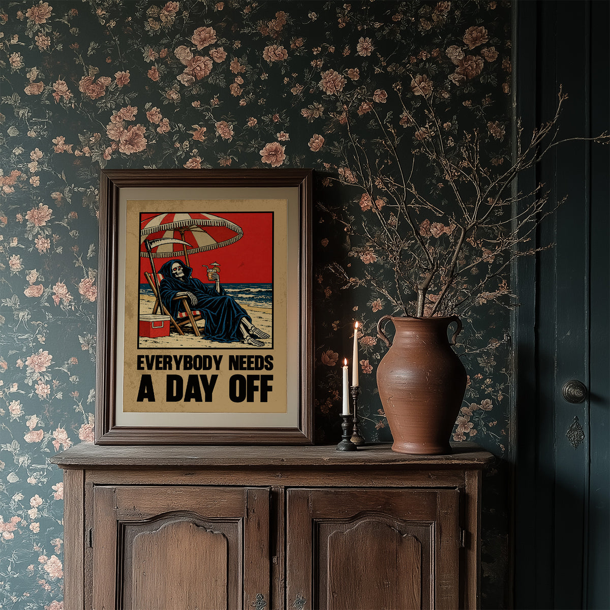 The Reaper Takes a Day Off, a hooded grim reaper in a deck chair under a striped umbrella on a red and cream beach poster, with the lettering EVERYBODY NEEDS A DAY OFF in bold black and tan below, in a retro print style, in a dark frame on a cabinet against floral wallpaper
